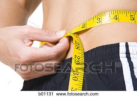Close-up of a young woman measuring her waist View Large Photo Image Stock Image - Close-up of a young woman measuring her waist. Fotosearch