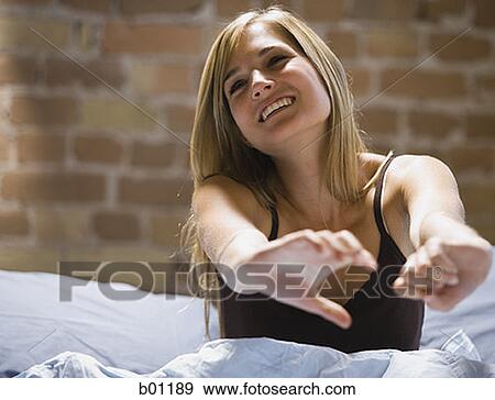 Close-up of a young woman sitting on a bed stretching View Large Photo Image Stock Photo - Close-up of a young woman sitting on a bed stretching. Fotosearch