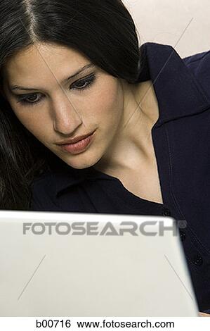 Close-up of a young woman using a laptop View Large Photo Image Stock Photograph - Close-up of a young woman using a laptop. Fotosearch