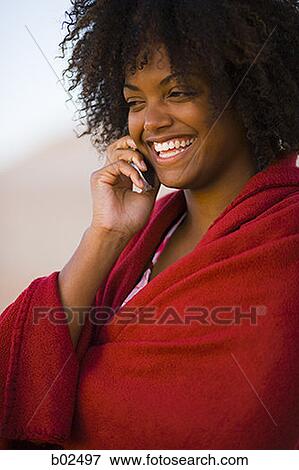 Close-up of a young woman wrapped in a towel talking on a mobile phone View Large Photo Image Stock Photo - Close-up of a young woman wrapped in a towel talking on a mobile phone. Fotosearch