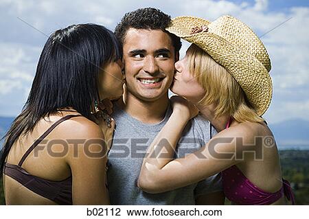 Close-up of two young women kissing a young man View Large Photo Image Stock Image - Close-up of two young women kissing a young man. Fotosearch