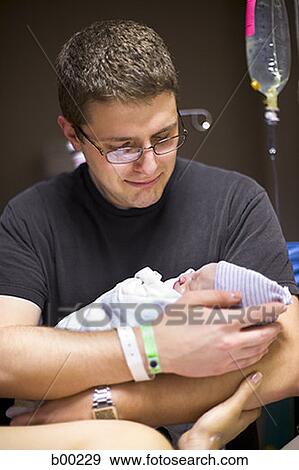 Father holding his newborn baby girl in a hospital ward View Large Photo Image Stock Photo - Father holding his newborn baby girl in a hospital ward. Fotosearch