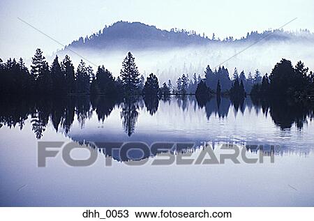 Fog-covered mountains and forest reflected on a lake View Large Photo Image Stock Image - Fog-covered mountains and forest reflected on a lake. Fotosearch