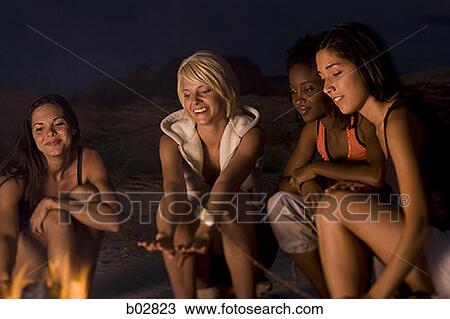 Four young women sitting at a campfire View Large Photo Image Stock Image - Four young women sitting at a campfire. Fotosearch