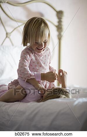 Girl sitting on top of her sister in a bedroom, smiling View Large Photo Image Stock Photography - Girl sitting on top of her sister in a bedroom, smiling. Fotosearch