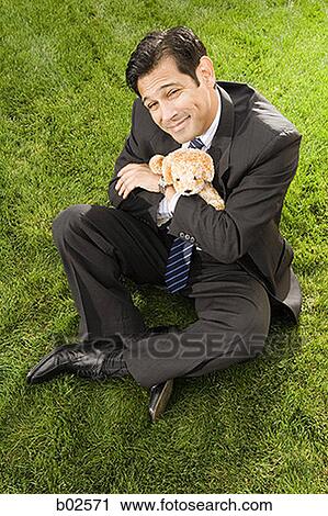 High angle view of a businessman with hugging a toy sitting on a grass View Large Photo Image Stock Image - High angle view of a businessman with hugging a toy sitting on a grass. Fotosearch