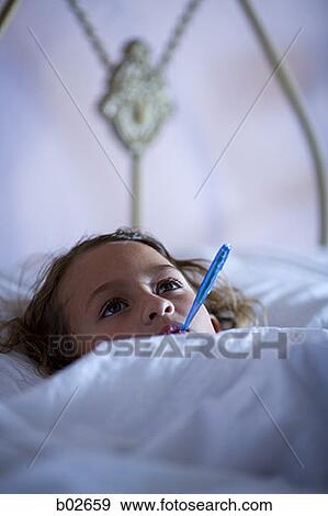 Stock Photo - High angle view of a girl with a thermometer in her mouth. Fotosearch