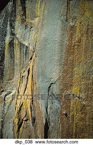 Stock Photo - High angle view of a person climbing up a steep rock formation. Fotosearch
