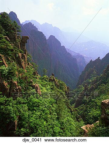 Stock Image - High-angle view of a tree-covered mountain side and mountain range. Fotosearch