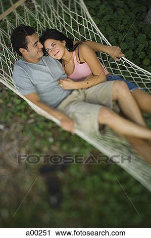 Stock Image - High angle view of a young couple lying on a hammock. Fotosearch