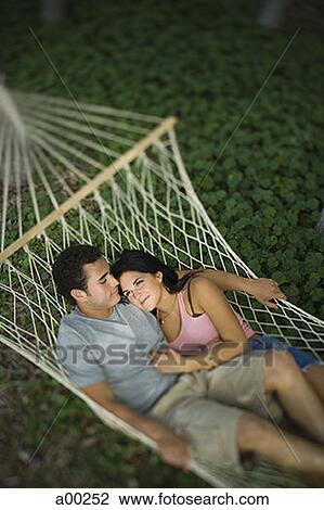 Stock Image - High angle view of a young couple lying on a hammock. Fotosearch