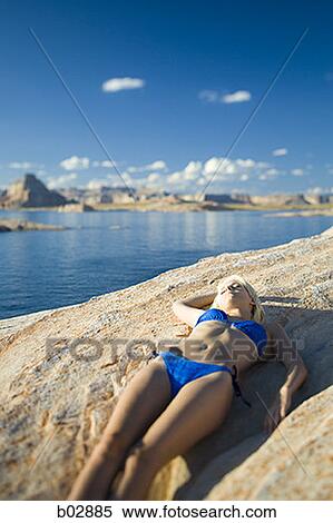 Stock Photography - High angle view of a young woman lying on a rock. Fotosearch