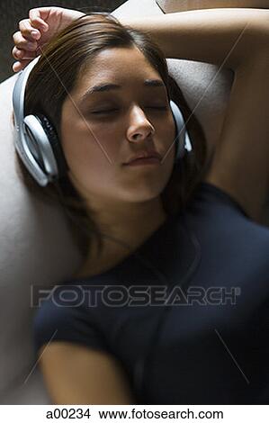Picture - High angle view of a young woman wearing headphones with her eyes closed. Fotosearch