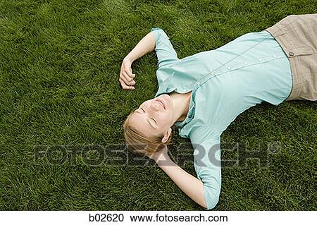 Stock Image - High angle view of a young woman sleeping on grass. Fotosearch