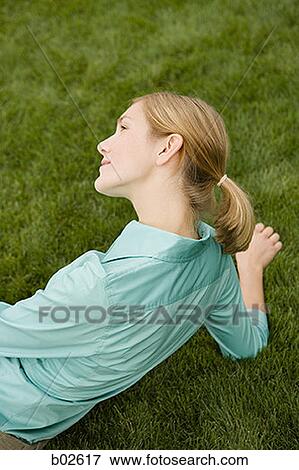 High angle view of a young woman sitting on a lawn View Large Photo Image Stock Photo - High angle view of a young woman sitting on a lawn. Fotosearch