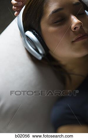 High angle view of a young woman listening to music on headphones View Large Photo Image Stock Photograph - High angle view of a young woman listening to music on headphones. Fotosearch