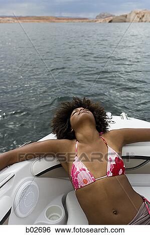 High angle view of a young woman resting on a speed boat View Large Photo Image Stock Photograph - High angle view of a young woman resting on a speed boat. Fotosearch