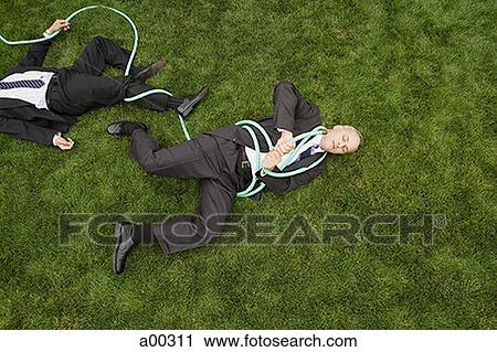 Stock Image - High angle view of two businessmen entangled in a garden hose. Fotosearch
