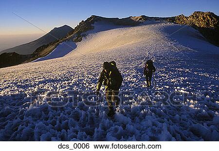 Stock Photograph - High angle view of two people trekking up a snow covered mountain. Fotosearch