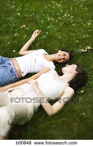 Stock Photo - High angle view of two teenage girls lying on the grass. Fotosearch