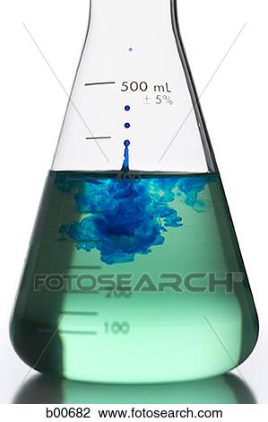 Stock Image - Liquid being poured into a conical flask with a test tube. Fotosearch
