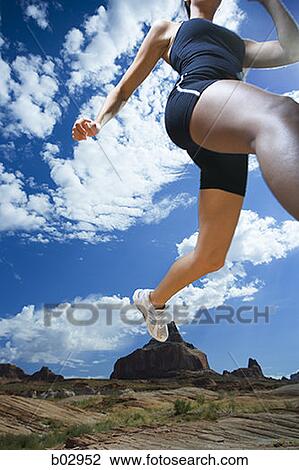 Low angle shot of a woman running in the desert View Large Photo Image Stock Image - Low angle shot of a woman running in the desert. Fotosearch