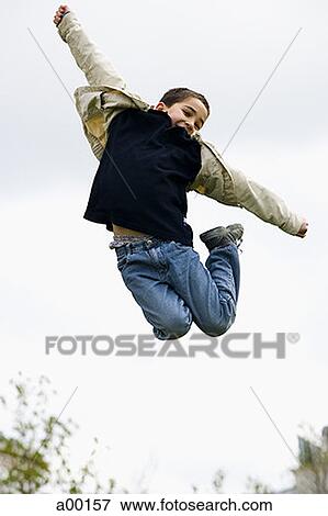 Low angle view of a boy jumping View Large Photo Image Stock Photo - Low angle view of a boy jumping. Fotosearch