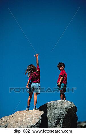 Low angle view of a brother and sister standing on rocks View Large Photo Image Stock Image - Low angle view of a brother and sister standing on rocks. Fotosearch