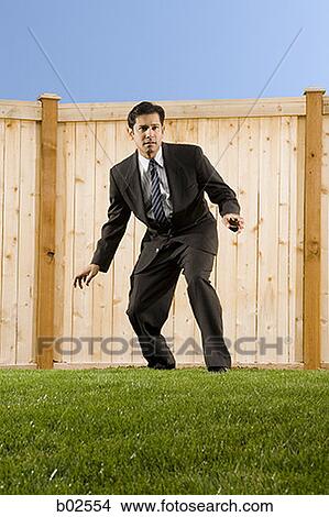 Low angle view of a businessman standing in front of a wall View Large Photo Image Picture - Low angle view of a businessman standing in front of a wall. Fotosearch