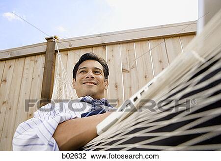 Low angle view of a businessman sitting on a hammock View Large Photo Image Stock Image - Low angle view of a businessman sitting on a hammock. Fotosearch
