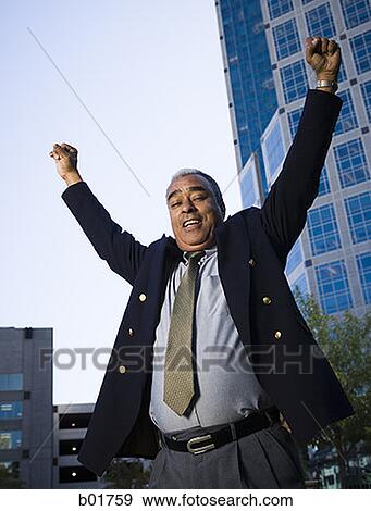 Low angle view of a businessman standing with his arms raised View Large Photo Image Stock Photo - Low angle view of a businessman standing with his arms raised. Fotosearch