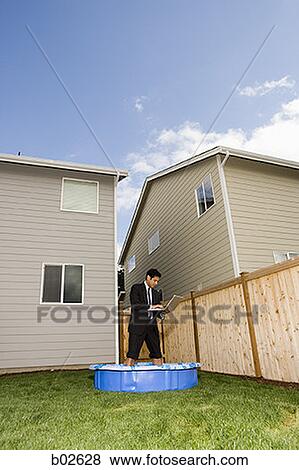 Low angle view of a businessman using a laptop while standing in a wading pool View Large Photo Image Stock Photo - Low angle view of a businessman using a laptop while standing in a wading pool. Fotosearch