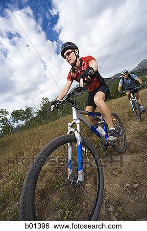 Low angle view of a couple mountain biking View Large Photo Image Stock Photograph - Low angle view of a couple mountain biking. Fotosearch