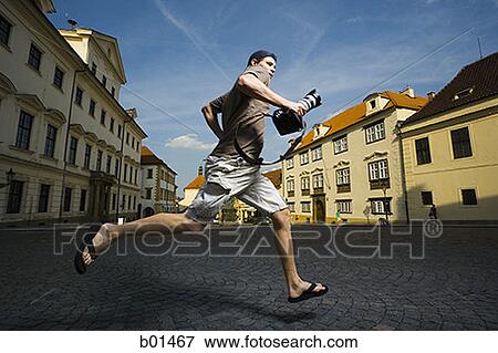 Low angle view of a man running with a camera View Large Photo Image Stock Photo - Low angle view of a man running with a camera. Fotosearch