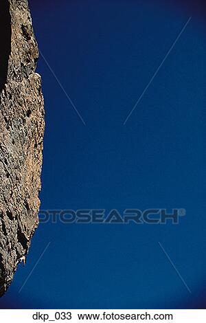 Low angle view of a person climbing a steep rock formation View Large Photo Image Stock Image - Low angle view of a person climbing a steep rock formation. Fotosearch