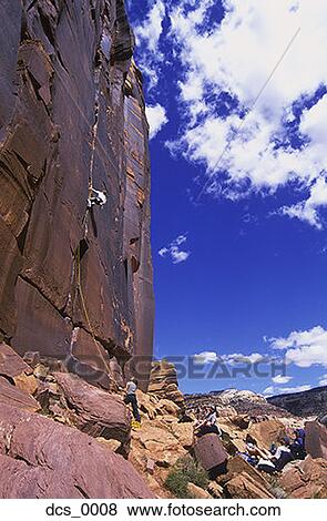 Stock Photo - Low angle view of a person rock climbing. Fotosearch