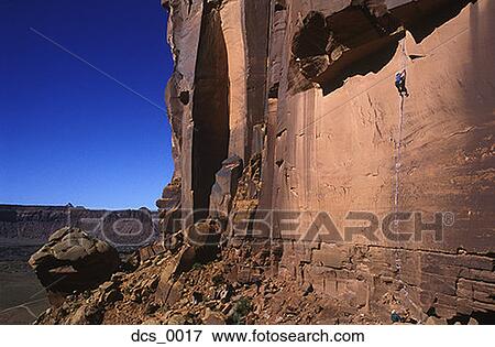 Stock Photo - Low angle view of a person rock climbing. Fotosearch