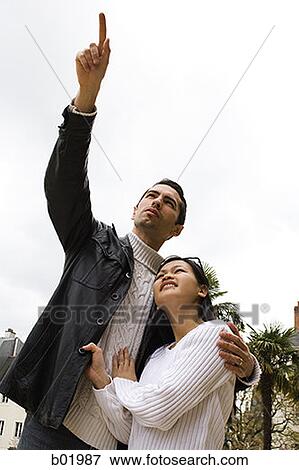 Stock Photo - Low angle view of a young couple looking up. Fotosearch