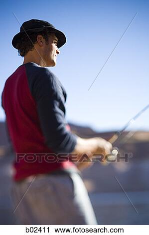 Low angle view of a young man fishing View Large Photo Image Stock Image - Low angle view of a young man fishing. Fotosearch