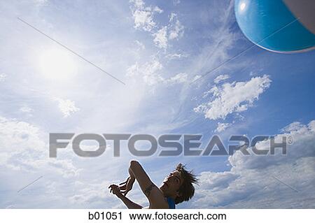 Low angle view of a young man hitting a beach ball View Large Photo Image Stock Image - Low angle view of a young man hitting a beach ball. Fotosearch