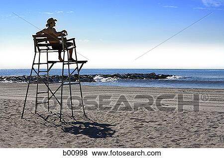 Low angle view of a young man sitting on a lifeguard chair View Large Photo Image Stock Photo - Low angle view of a young man sitting on a lifeguard chair. Fotosearch