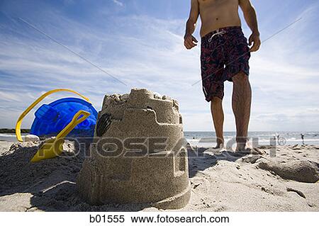 Low angle view of a young man standing on the beach View Large Photo Image Stock Photography - Low angle view of a young man standing on the beach. Fotosearch