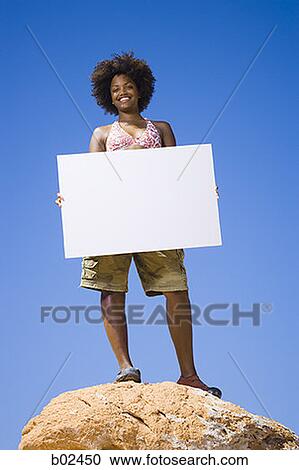 Low angle view of a young woman holding a blank sign View Large Photo Image Stock Image - Low angle view of a young woman holding a blank sign. Fotosearch