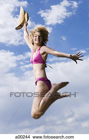 Low angle view of a young woman jumping View Large Photo Image Picture - Low angle view of a young woman jumping . Fotosearch