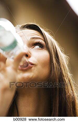 Low angle view of a young woman drinking water from a bottle View Large Photo Image Stock Photo - Low angle view of a young woman drinking water from a bottle. Fotosearch