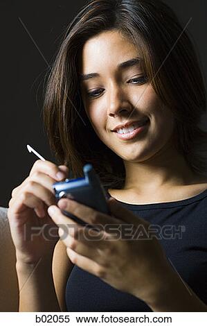 Low angle view of a young woman operating a personal organizer View Large Photo Image Stock Photography - Low angle view of a young woman operating a personal organizer. Fotosearch