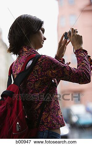 Low angle view of a young woman taking a photograph View Large Photo Image Stock Photo - Low angle view of a young woman taking a photograph. Fotosearch