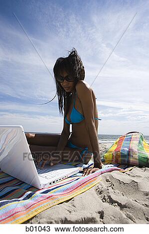 Low angle view of a young woman using a laptop on the beach View Large Photo Image Stock Image - Low angle view of a young woman using a laptop on the beach. Fotosearch