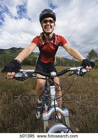 Low angle view of an adult woman riding a bicycle View Large Photo Image Stock Photography - Low angle view of an adult woman riding a bicycle. Fotosearch