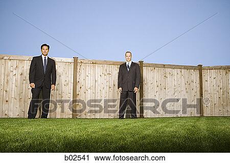 Low angle view of two businessmen standing in front of a fence View Large Photo Image Stock Image - Low angle view of two businessmen standing in front of a fence. Fotosearch